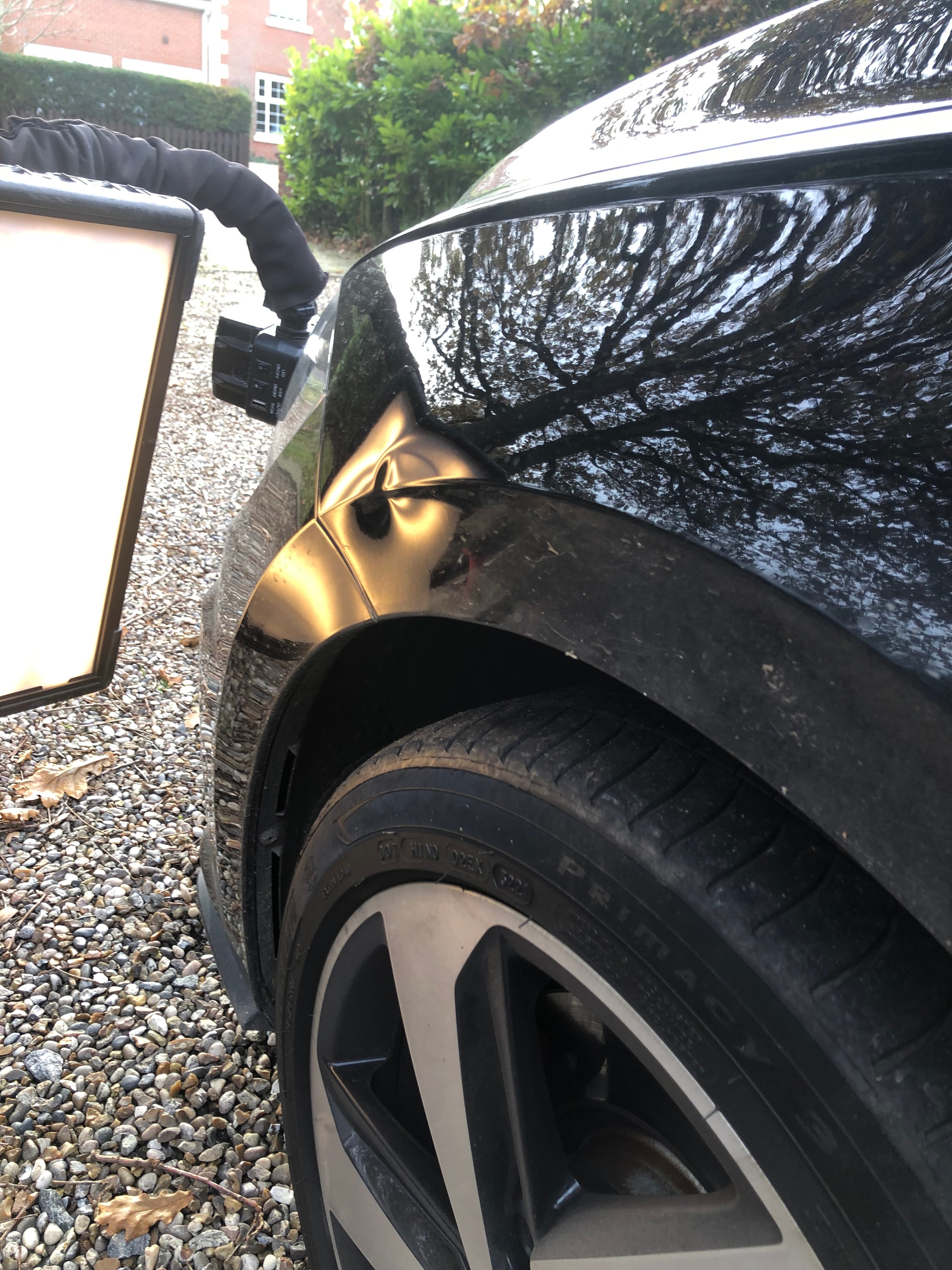 Dirty black car with dent — before paintless dent repair