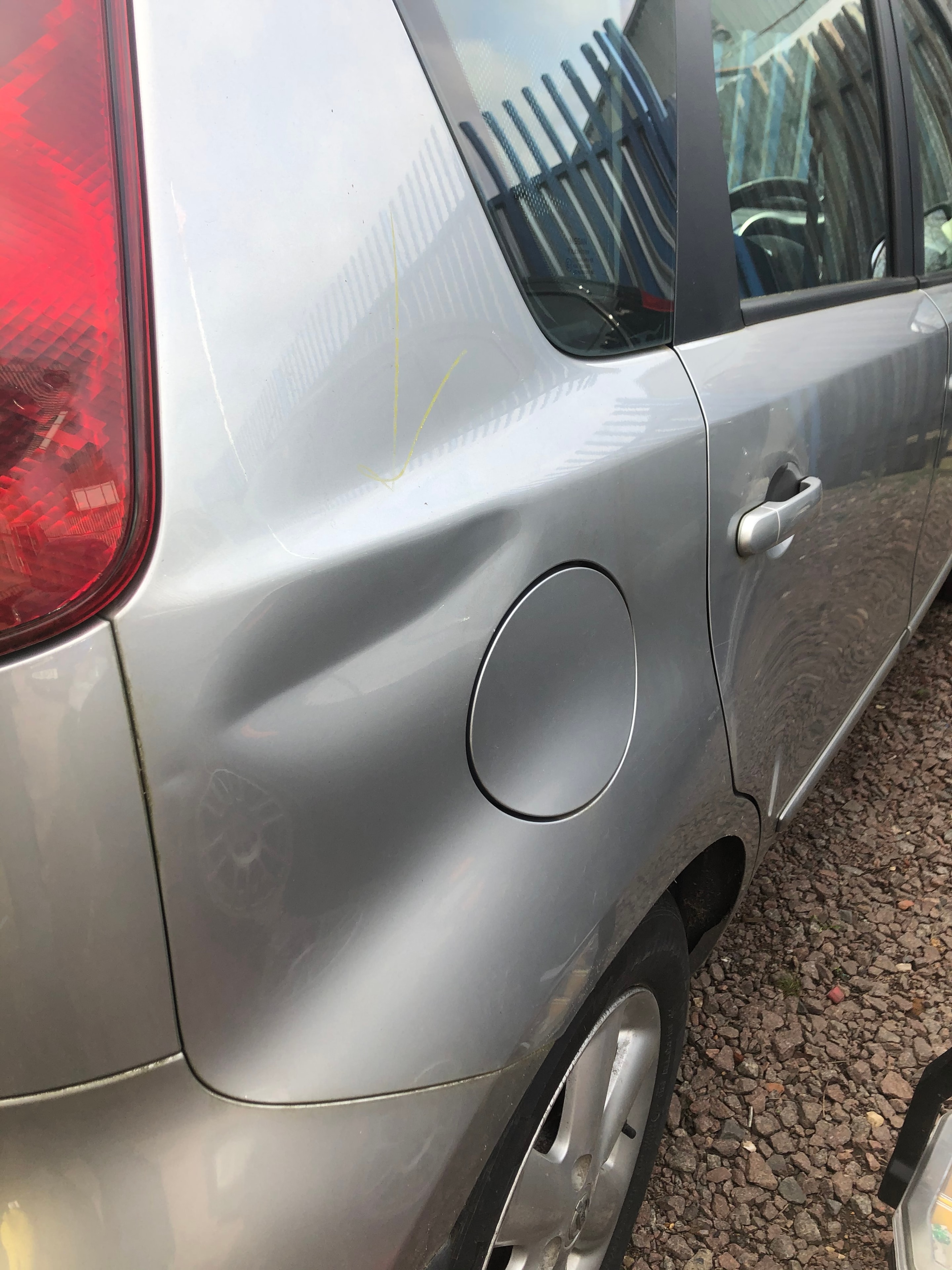 Silver car dented door panel — before repair